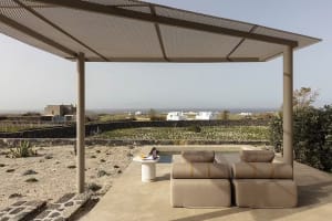 A minimalist outdoor lounge area with a concrete structure and seating, overlooking a scenic landscape.