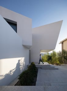 A modern residential exterior with a curved concrete wall and large window