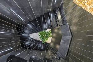A modern staircase with black metal railings and marble steps and flooring.