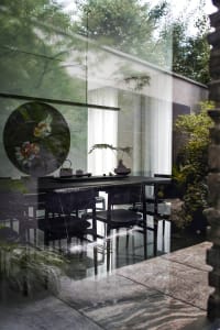 Modern minimalist interior design featuring glass walls and a serene garden view.