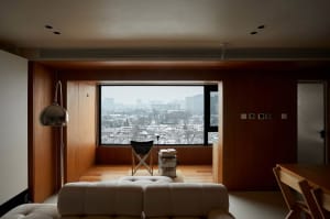 A minimalist living room with a window overlooking a cityscape.