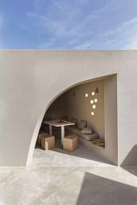 A minimalist-themed concrete outdoor living space with a curved seating area and a table setting.