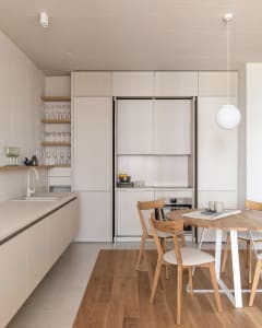 A modern minimalist kitchen with light wooden furniture and clean, sleek appliances.