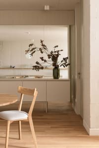 Modern minimalist kitchen interior with wood accents and a vase of dried branches.