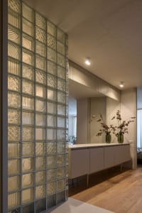 Doorway framed by a patterned glass partition and a light-colored wooden floor in a modern residential interior setting.