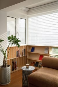 Modern living room featuring a wooden bookshelf with books and plants.