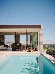 Modern residential exterior featuring large glass panels and a swimming pool.