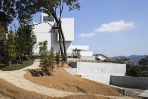 A modern minimalist home exterior with a concrete wall and a white building.