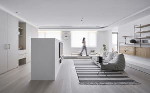 A modern minimalist living room with a wooden floor, white walls, and a comfortable seating area.
