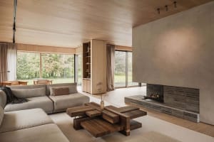 A minimalist living room with a large wood coffee table and a fireplace.