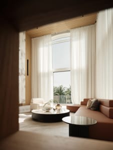 Modern living room with transparent curtains, leather sofa, and marble coffee table.