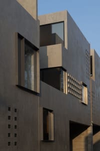 Concrete building exterior with geometric windows and vertical lines.
