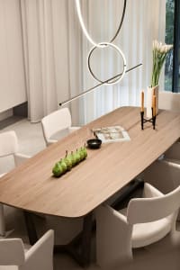 A modern dining room featuring a wooden table with a minimalist vase and decorative items.