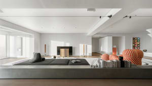 Modern living room with concrete seating, minimalist decor, and high ceilings.