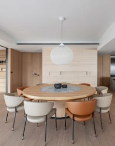 Modern dining room featuring a round wooden table with a marble insert centerpiece, surrounded by stylish chairs and natural 