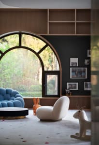 A modern playroom featuring wooden furniture and a large window with an arched design.