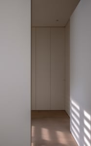 A minimalist interior with white walls and wooden flooring.
