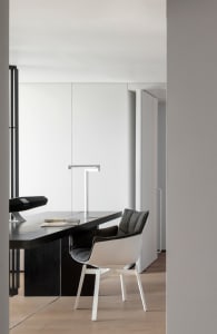 A modern, minimalist office space with a sleek black desk and contemporary chair.