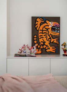 A canvas painting featuring a vibrant tiger illustration on a white shelving unit in a minimalist room setting.