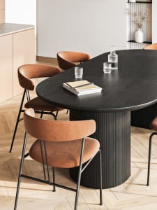 A modern dining room featuring a wooden table with orange upholstered chairs and a minimalist design.