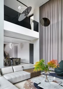 A modern living room featuring minimalist furniture, a marble table, grey curving sofa, and contemporary lighting.