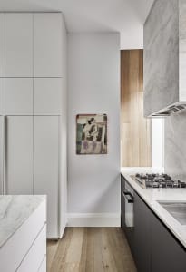 A modern minimalist kitchen with marble countertops and cabinets.