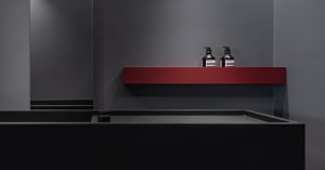 Modern bathroom with minimalist design featuring a concrete sink and a red shelf with dark bottles.