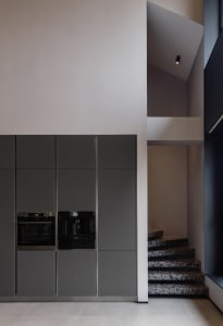 Modern kitchen with sleek gray cabinets and marble counters.