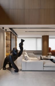 Modern living room featuring a large white sofa, a black sculpture, and wooden paneling on the walls and ceiling.