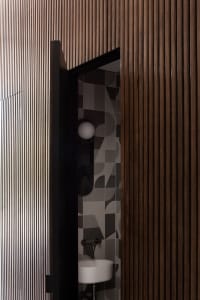 A modern bathroom with a wooden wall and geometric tiles.