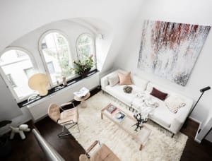 Modern, white-themed living room featuring a cozy sofa, minimalist chairs, and abstract art, designed for comfort and style.