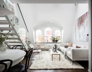 A modern apartment living room with white walls, a white sofa, and a white round dining table.
