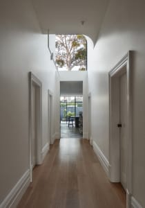Modern white interior design hallway with hardwood floors and natural light from skylight.