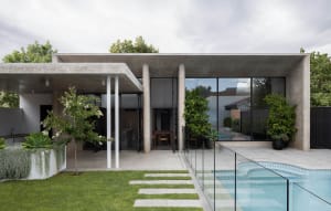 A modern minimalist home exterior featuring concrete pool, columns, and a well-maintained lawn with walkways.