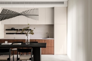 Modern residential kitchen with black dining table, wooden cabinets, and marble countertops.
