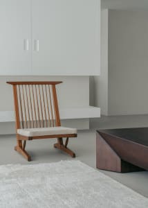 A minimalist living room featuring wooden furniture with a low coffee table and a cushioned chair.