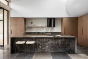 A modern kitchen with a marble island and wooden cabinets.