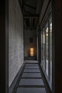 A minimalist corridor with stone pavement, gravel, and ambient lighting.