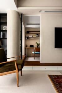 A modern minimalist living room and office space with a wooden chair, concrete floors, and floating shelves.