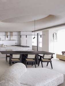 An image depicting a modern open-plan living, dining, and kitchen space featuring a concrete floor and a central wooden dinin
