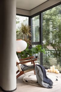 A modern living room setting with indoor plants, a wooden chair, and a cozy atmosphere.