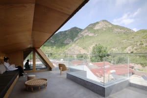 A modern residential balcony featuring wooden elements and a view of mountains.