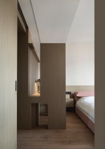 A minimalist bedroom featuring wooden furniture and floors.