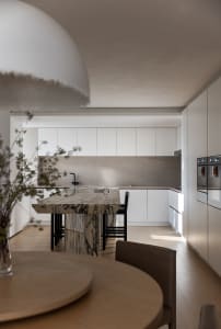 Modern minimalist kitchen featuring marble countertop and white cabinetry.