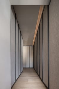 A minimalist corridor with taupe textured walls and wooden flooring.