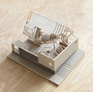 A detailed wooden model of a residential home, showcasing its structure and design.