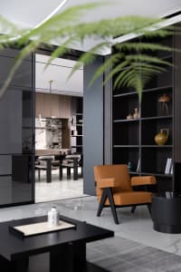 Modern living room featuring dark wood furniture, marble accents, and a leather armchair.