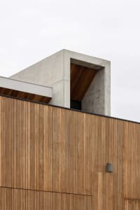 Modern building exterior featuring wooden cladding and concrete structural elements.