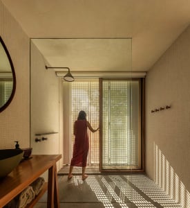 A minimalist bathroom with tiled walls, glass window, and wooden accents.