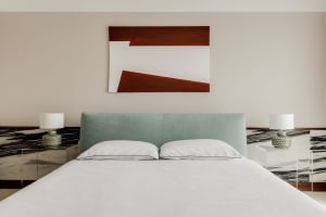 A modern minimalist bedroom with a green upholstered headboard and two white pillows.